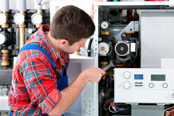 HVAC technician inspecting and repairing boiler controls in Lehi