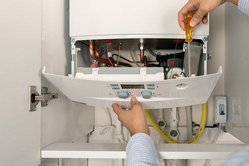 HVAC technician repairing an indoor boiler in Lehi
