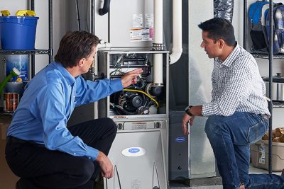 65df8c11f3e4c468cbd351a5_furnace repair vs replacement – Copy HVAC technician explaining furnace repair and maintenance to a homeowner in Lehi, UT